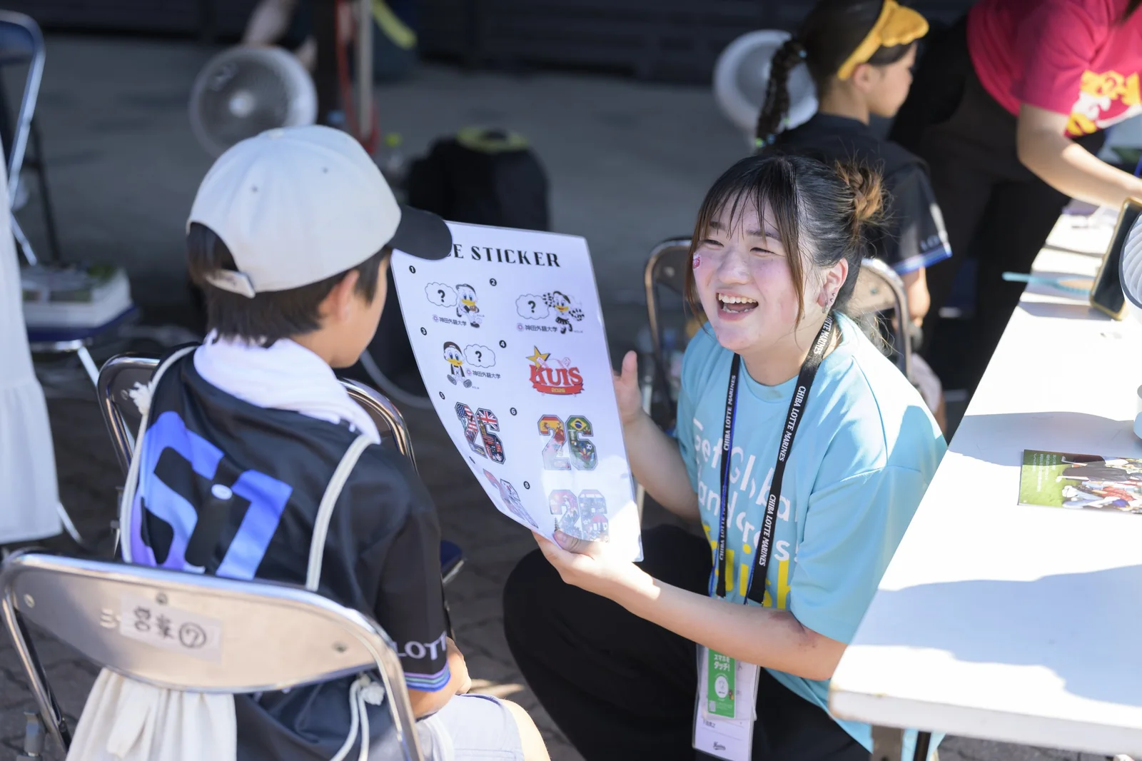 マリーンズのイベントで来場者に説明する神田外語大学の学生