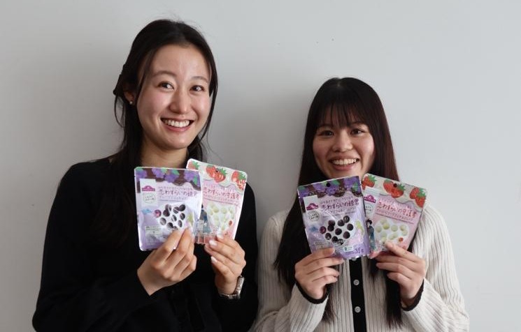 開発に協力したグミ＆チョコレートの商品を手に笑顔を見せる学生2人